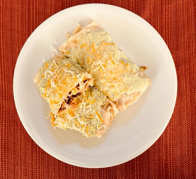 Black bean and corn enchiladas topped with a cilantro sauce and cheese.