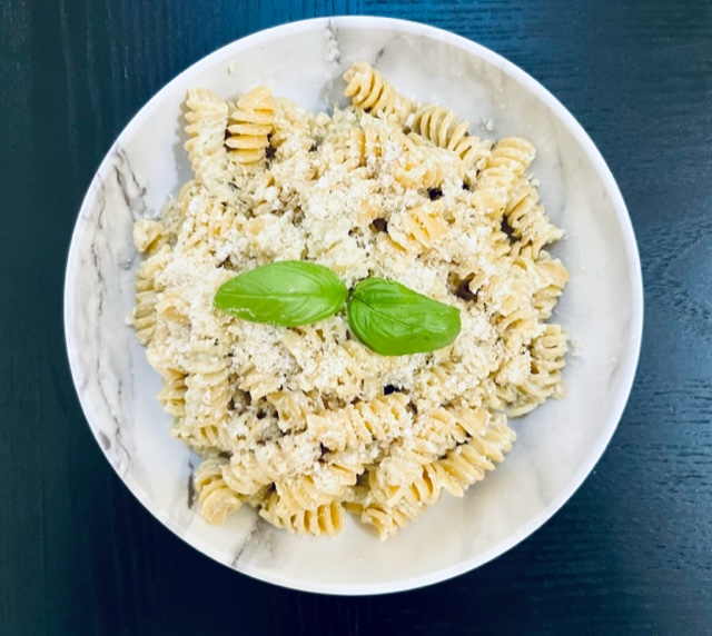Creamy pesto pasta topped with basil and parmesan