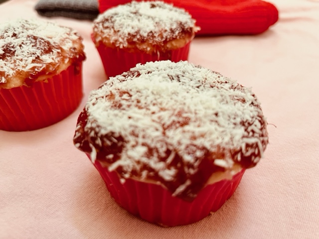 Eggless cupcakes topped with jam and dessicated coconut