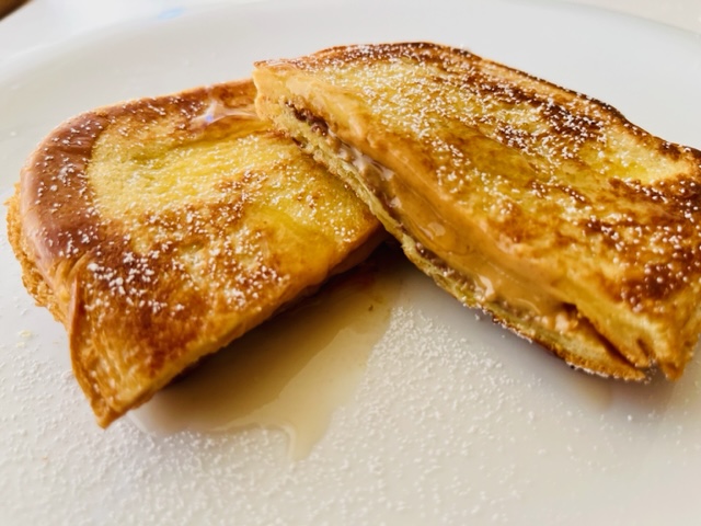 Gourmet peanut butter chocolate sandwich topped with powdered sugar and maple syrup