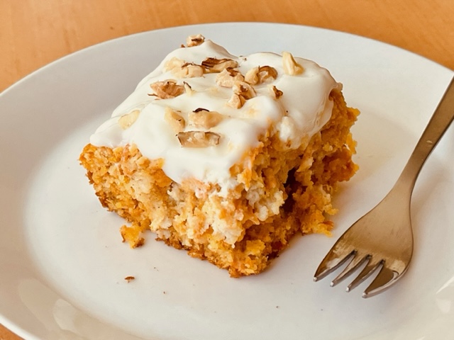 Carrot and pineapple cake topped with a cream cheese frosting and chopped walnuts
